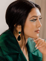 Woman in green outfit wearing silver earrings with simulated diamonds and emerald stone.